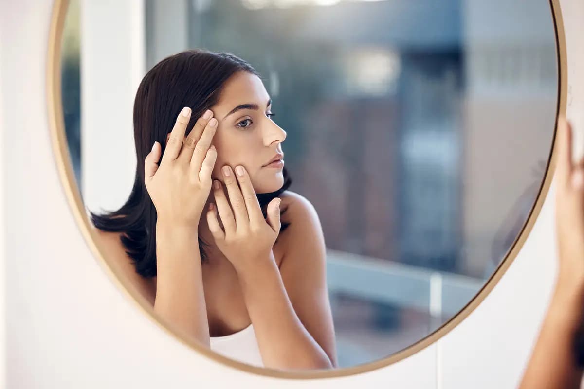 woman by a mirror checking for wrinkles while in bathroom