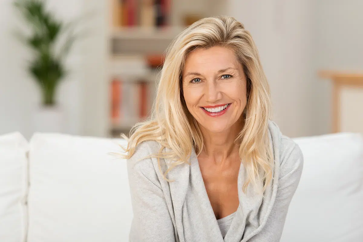 Happy mature blonde woman on a white couch